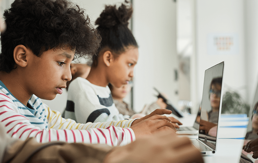 young kids in a classroom working on laptops
