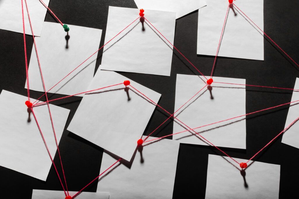 A detective board with paper connected by red string, representing the collection of evidence for network change validation