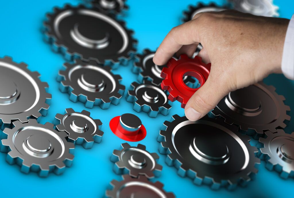 A hand removing a crucial gear from a system of gears, representing unsuccessful tool consolidation
